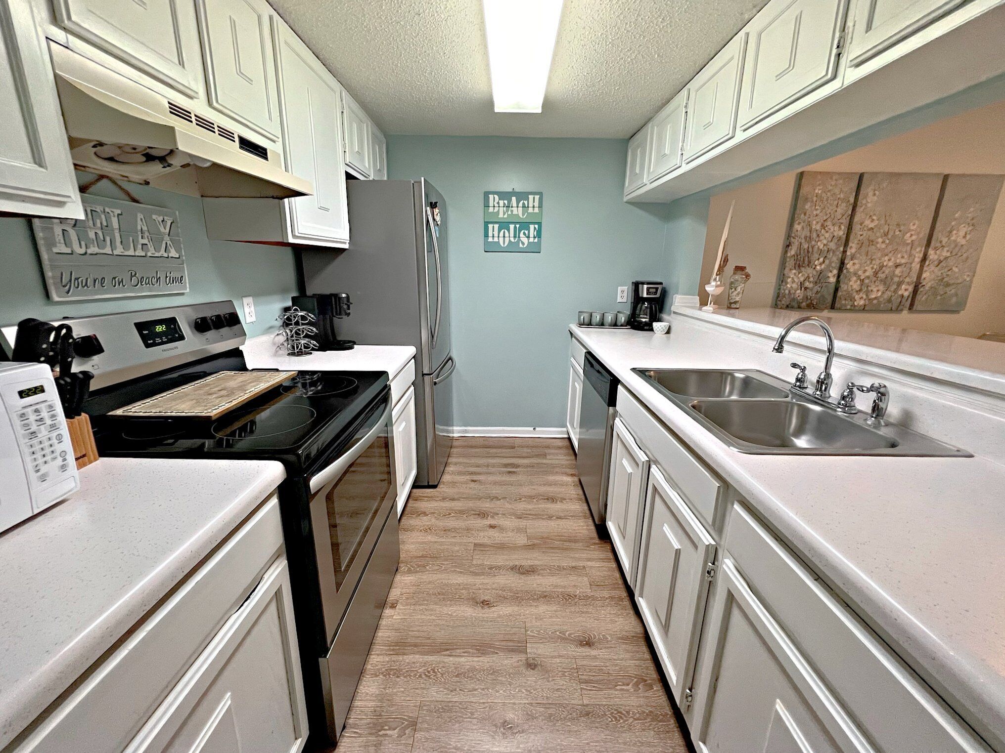 A kitchen with white cabinets, a stainless steel refrigerator, a coffee maker, and a sink.