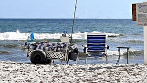 Een strandscène met een viskar, een gestreepte stoel en een bord met informatie over het verwijderen van persoonlijke bezittingen.