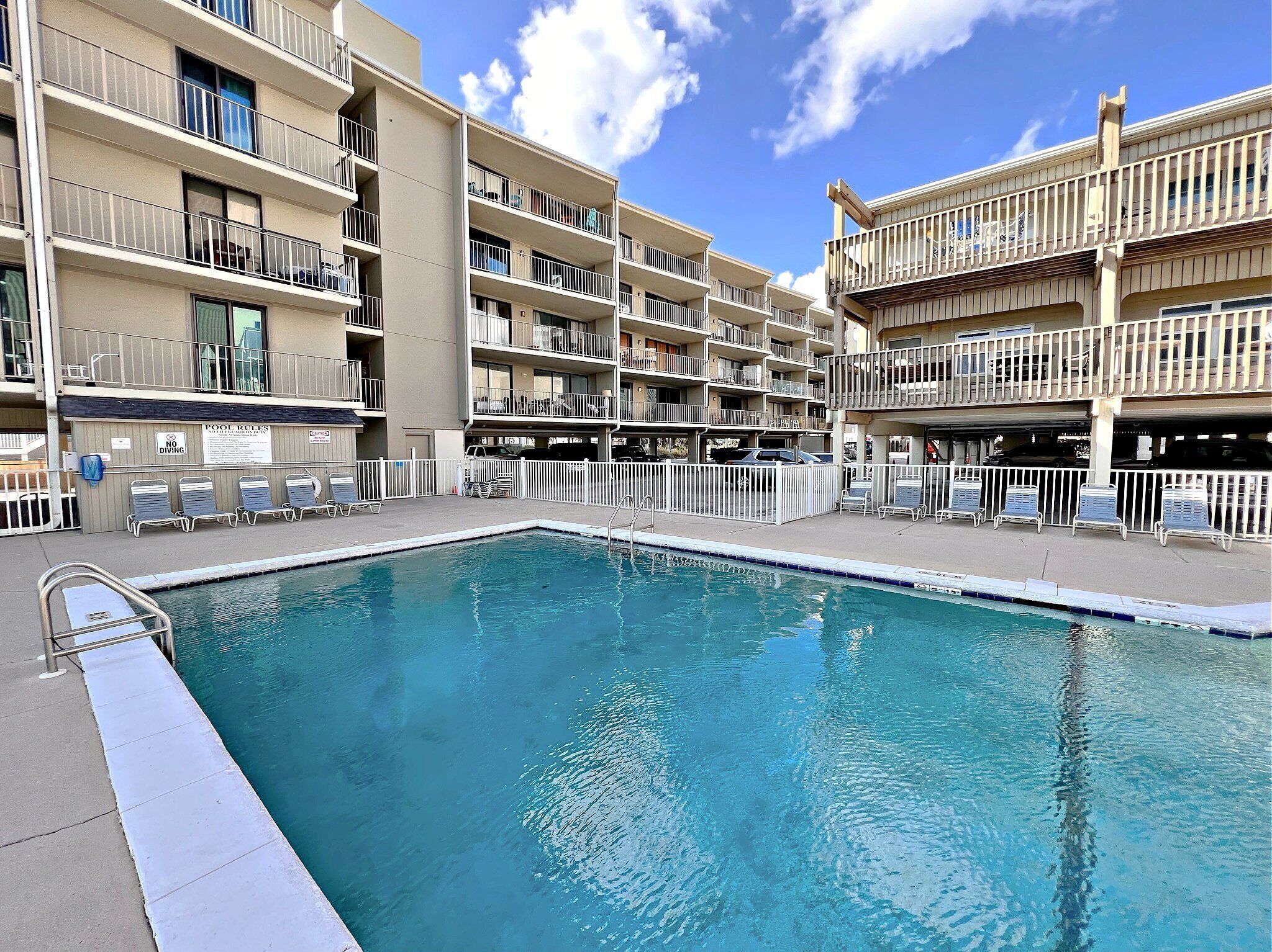A swimming pool with lounge chairs and a sign indicating no diving.