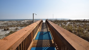 Une promenade en bois menant à la plage, avec un ciel dégagé.