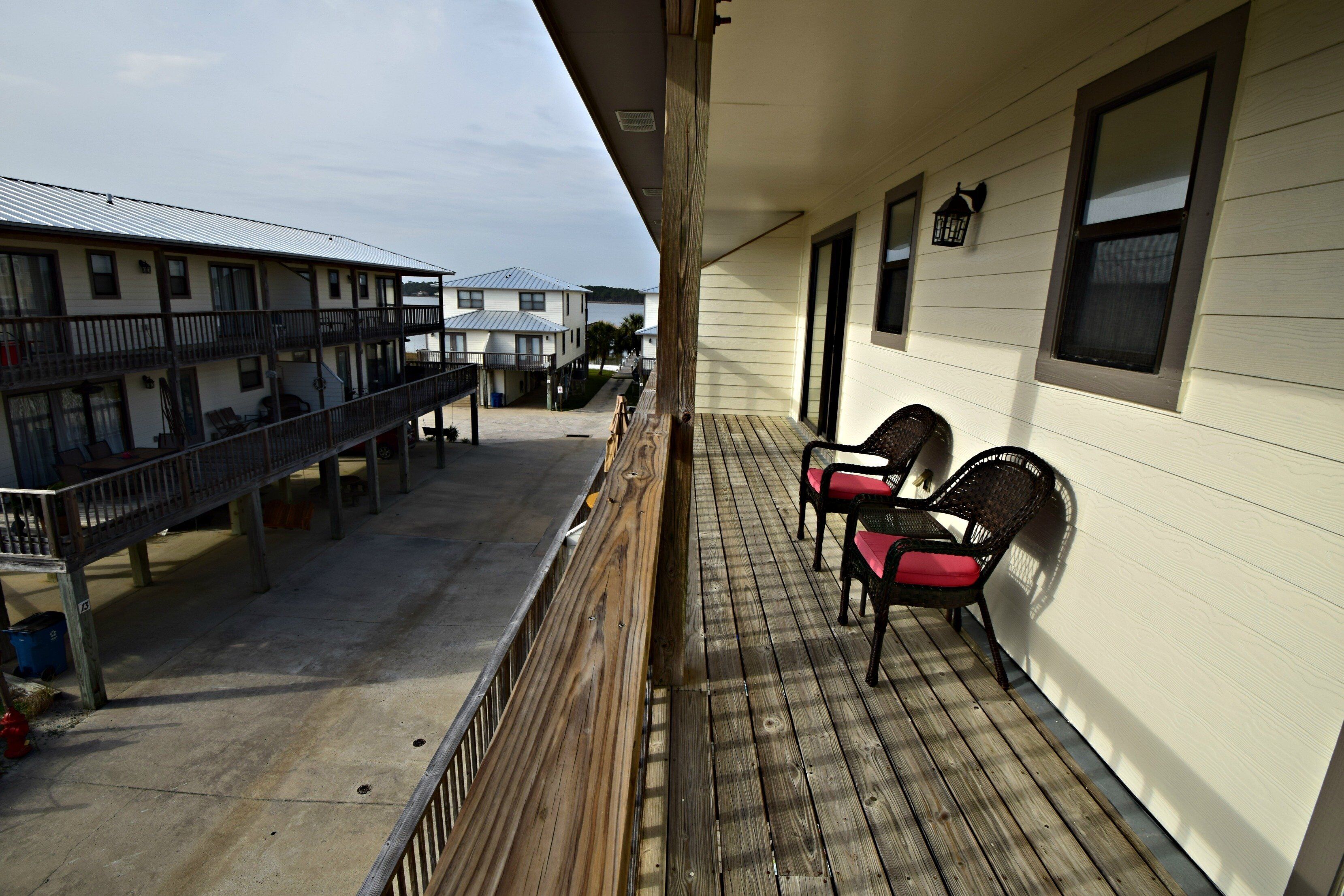 A balcony with wooden railings, a small table, and two chairs.