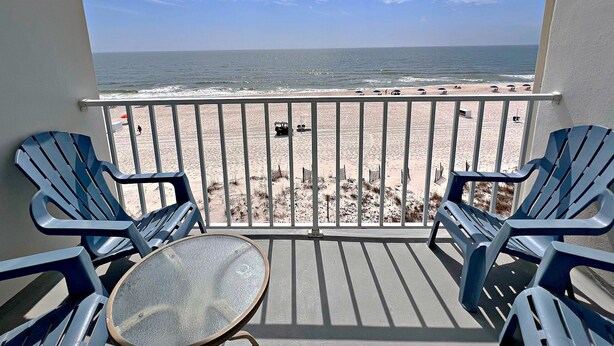 Ein Balkon mit Blick auf den Strand, ausgestattet mit einem Tisch und Stühlen.