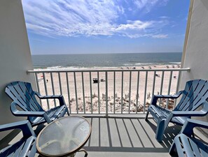 A balcony with a view of the beach, featuring a table and chairs. - Island Shores (Gulf Shores)