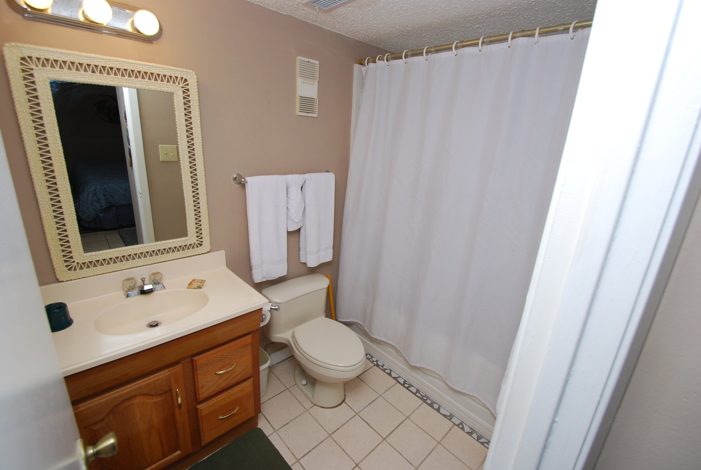 A bathroom with a sink, mirror, toilet, and shower curtain.