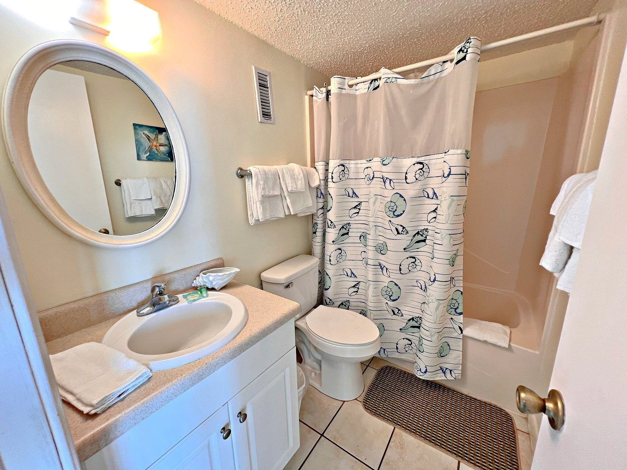 Une salle de bain avec un lavabo, des toilettes et un rideau de douche.