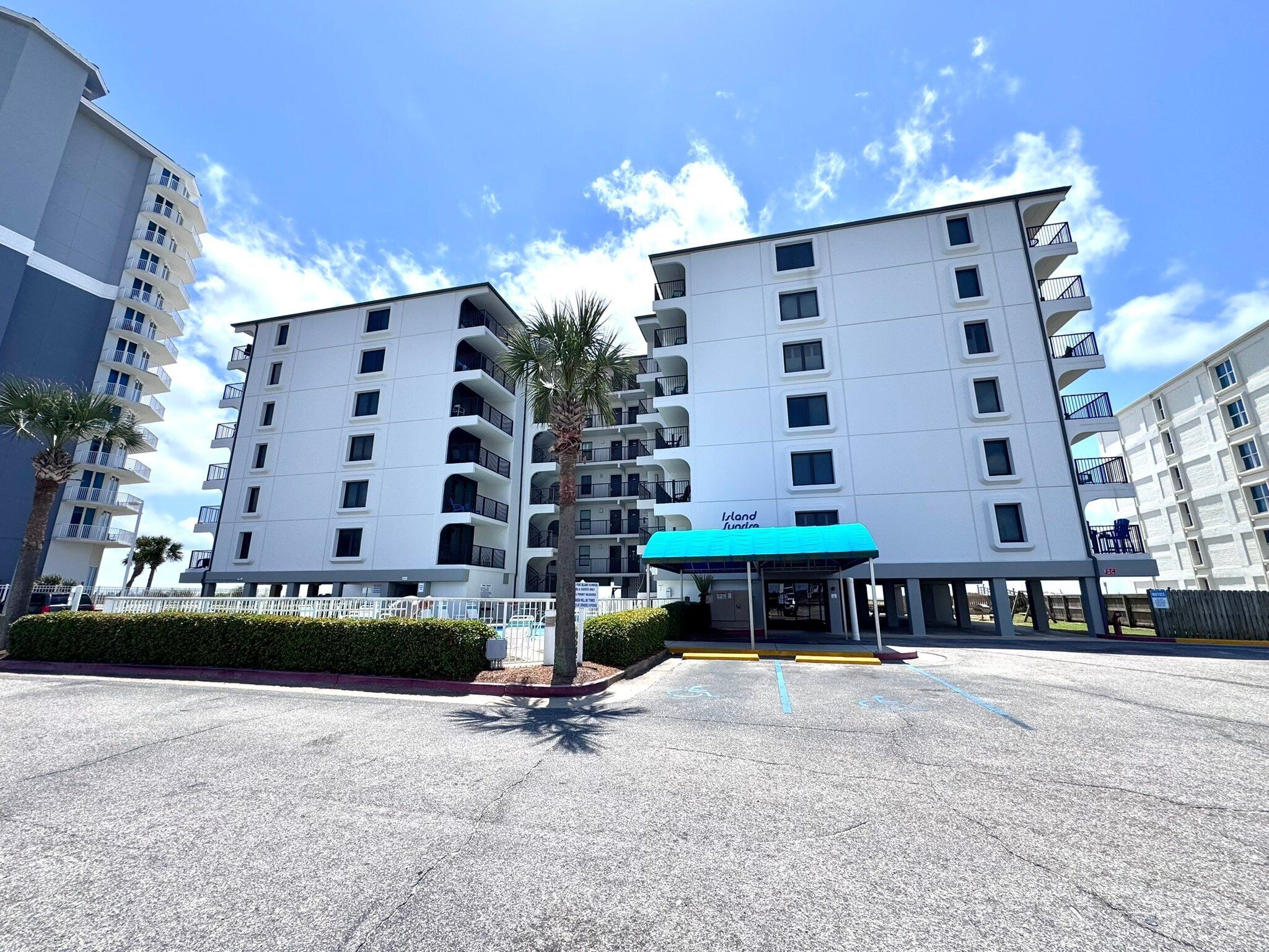 A modern multi-story hotel with balconies, a covered entrance, and a parking area with handicapped accessibility.
