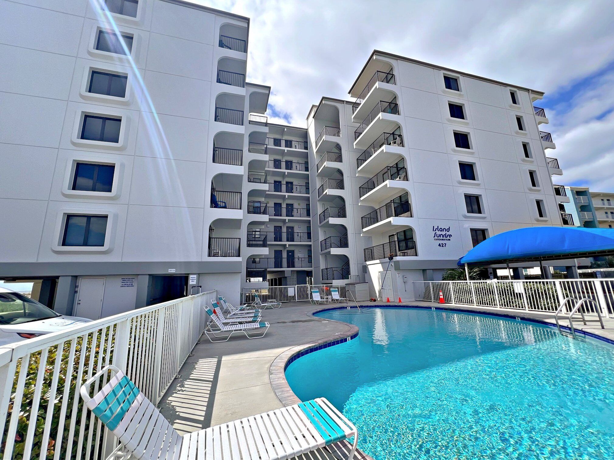 Ein modernes Hotel mit Poolbereich, mehreren Balkonen und einem Schild mit der Aufschrift 'Island Sundive'.