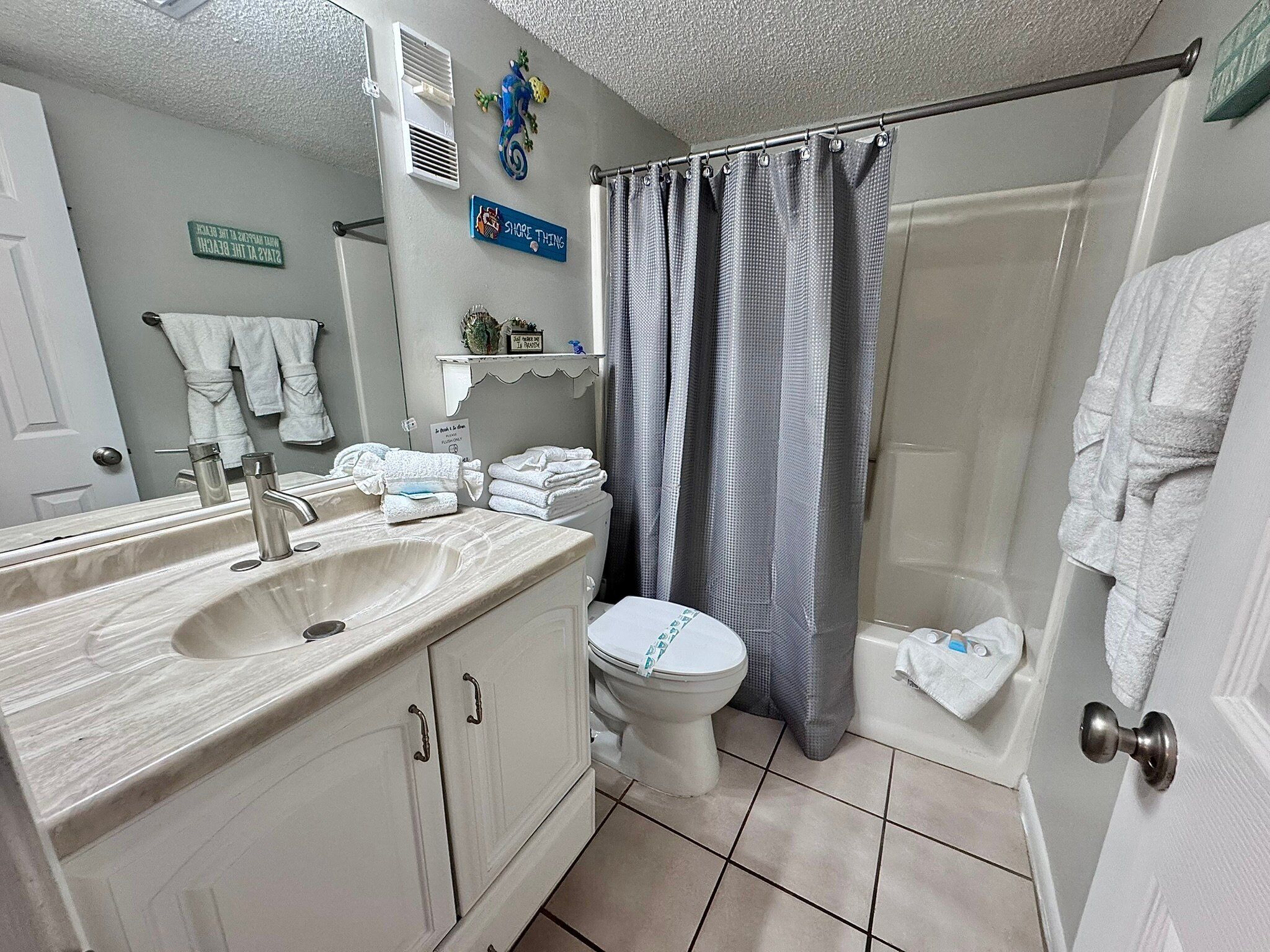 Un baño con lavamanos, inodoro, cortina de ducha y toallas.