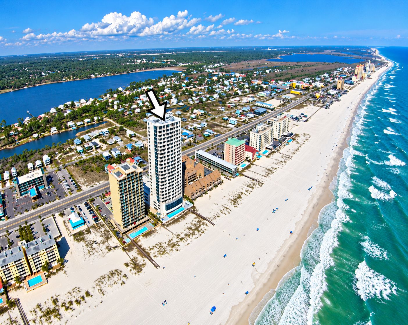 A coastal cityscape with a prominent high-rise hotel, beachfront properties, and a marina.