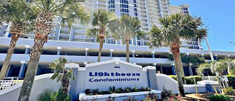A multi-story building with a sign reading "Lighthouse Condominiums."