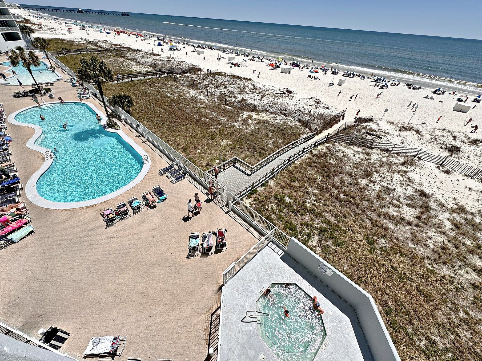A beach resort with a swimming pool, beach chairs, and umbrellas.