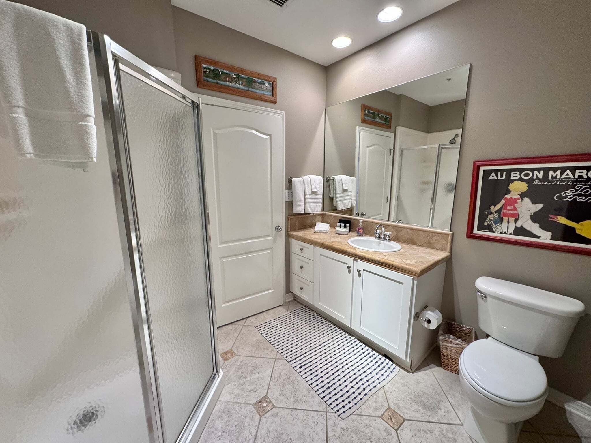 Une salle de bain équipée d’une douche, de toilettes, d’un lavabo et d’un miroir.
