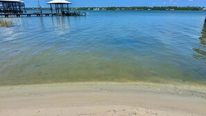 En strand med klart vatten, en sandstrand och en brygga med olika konstruktioner.