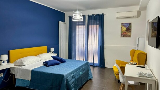 A hotel room with a bed, a desk, a chair, and a TV. - Il Ruggi  (Salerno)