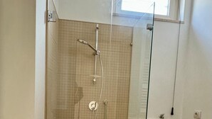 A bathroom with a glass-enclosed shower, a white sink, and a toilet. - Il Ruggi  (Salerno)