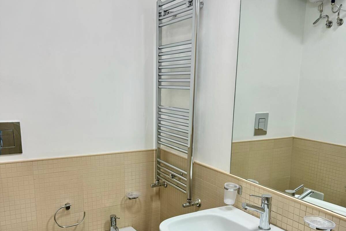 Un baño con inodoro, bidé y un lavamanos grande con espejo.