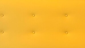 A close-up of a blue and yellow upholstered headboard with circular buttons. - Il Ruggi  (Salerno)