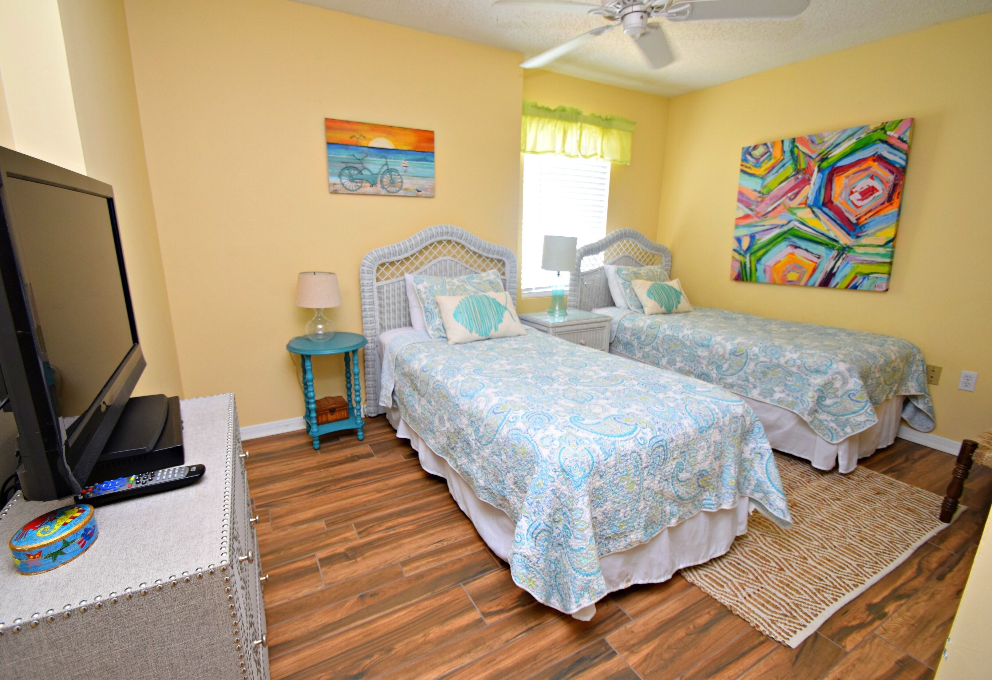 A hotel room with two beds, a television, and artwork on the walls.