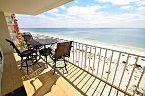 Un balcon avec une table et des chaises donnant sur une plage.