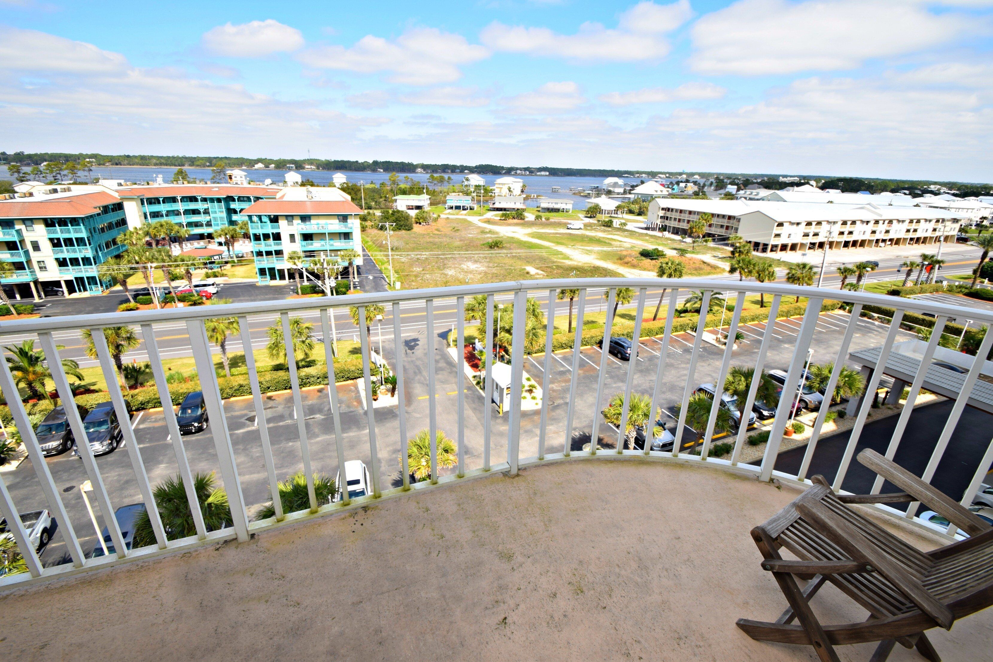 Ein Balkon mit Blick auf einen Parkplatz, Gebäude und ein Gewässer.