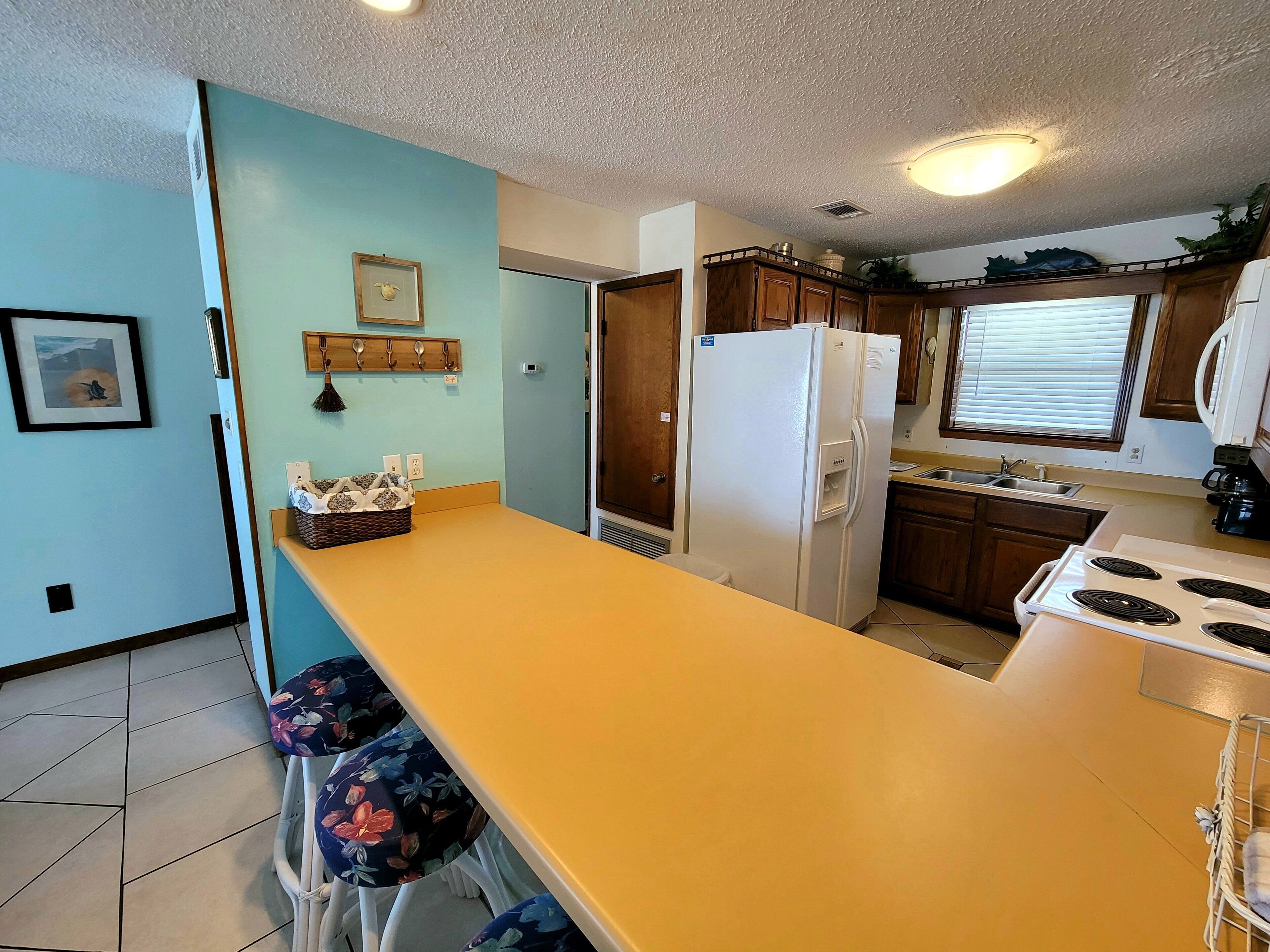 Una cocina compacta con una isla central, armarios de madera y un refrigerador.