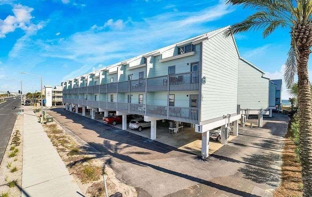 A multi-story motel with a flat roof and balconies, located adjacent to a road with a sidewalk.