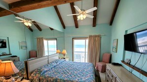 A bedroom with a bed, a desk, a chair, a TV, and a window with a view. - Ocean Reef (Gulf Shores)