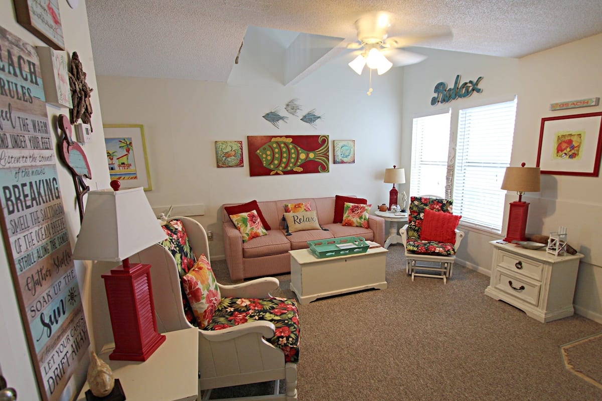 A cozy living room with a sofa, chairs, a coffee table, and a ceiling fan.
