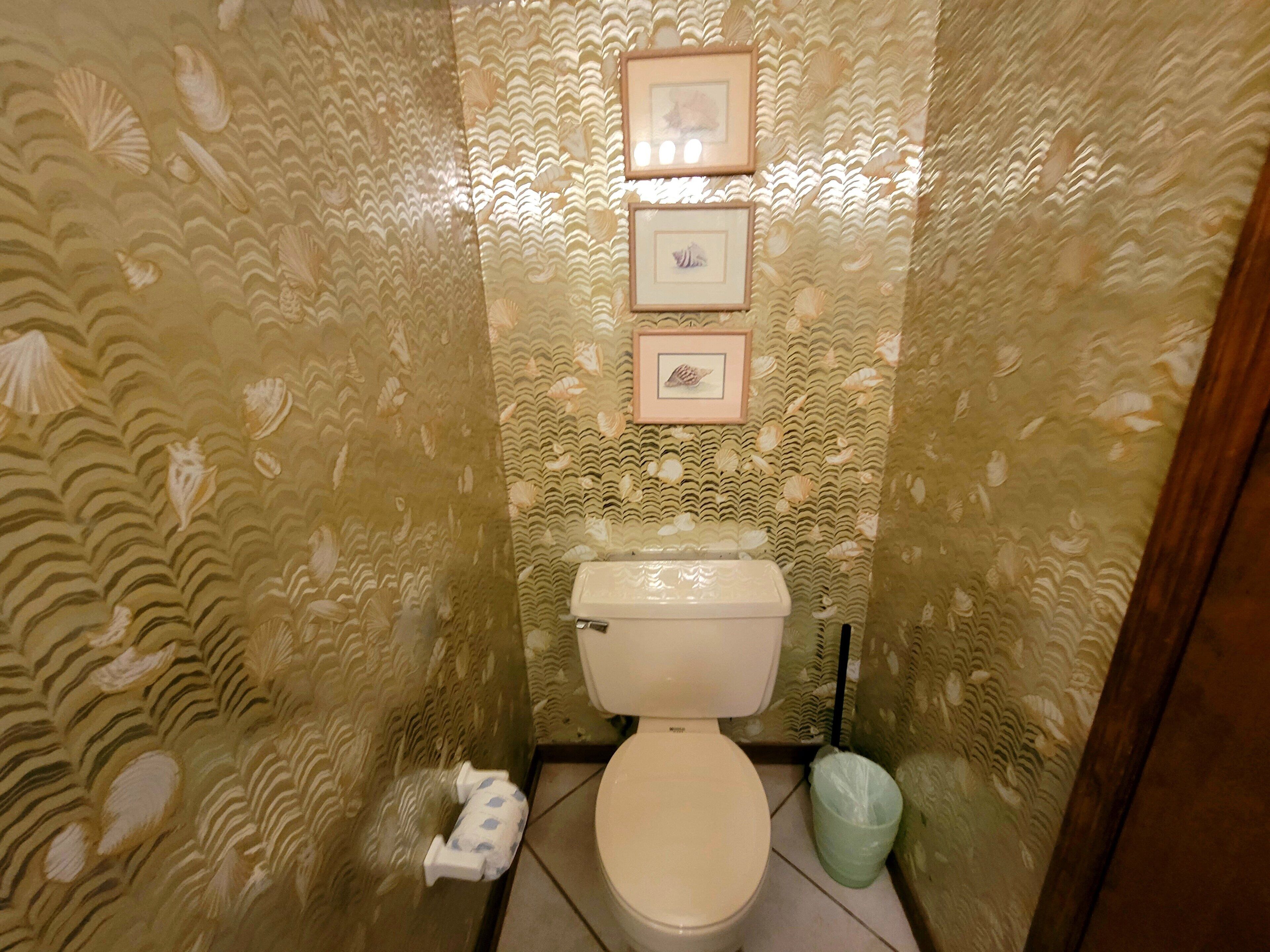 Une salle de bain équipée de toilettes, d’une poubelle et d’un porte-rouleau de papier toilette.