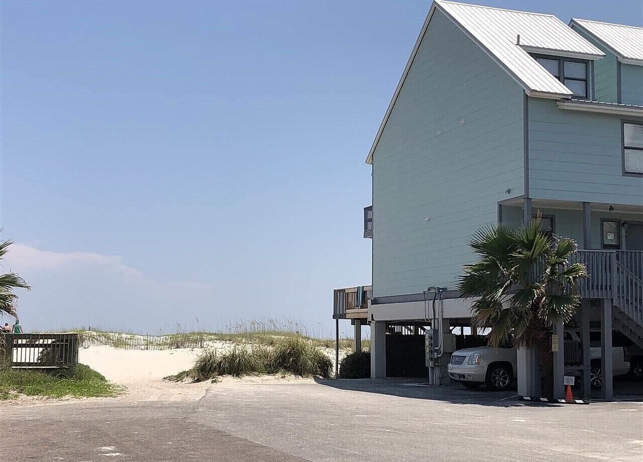 Ein Gebäude direkt am Strand mit Parkplatz und überdachtem Zugang.