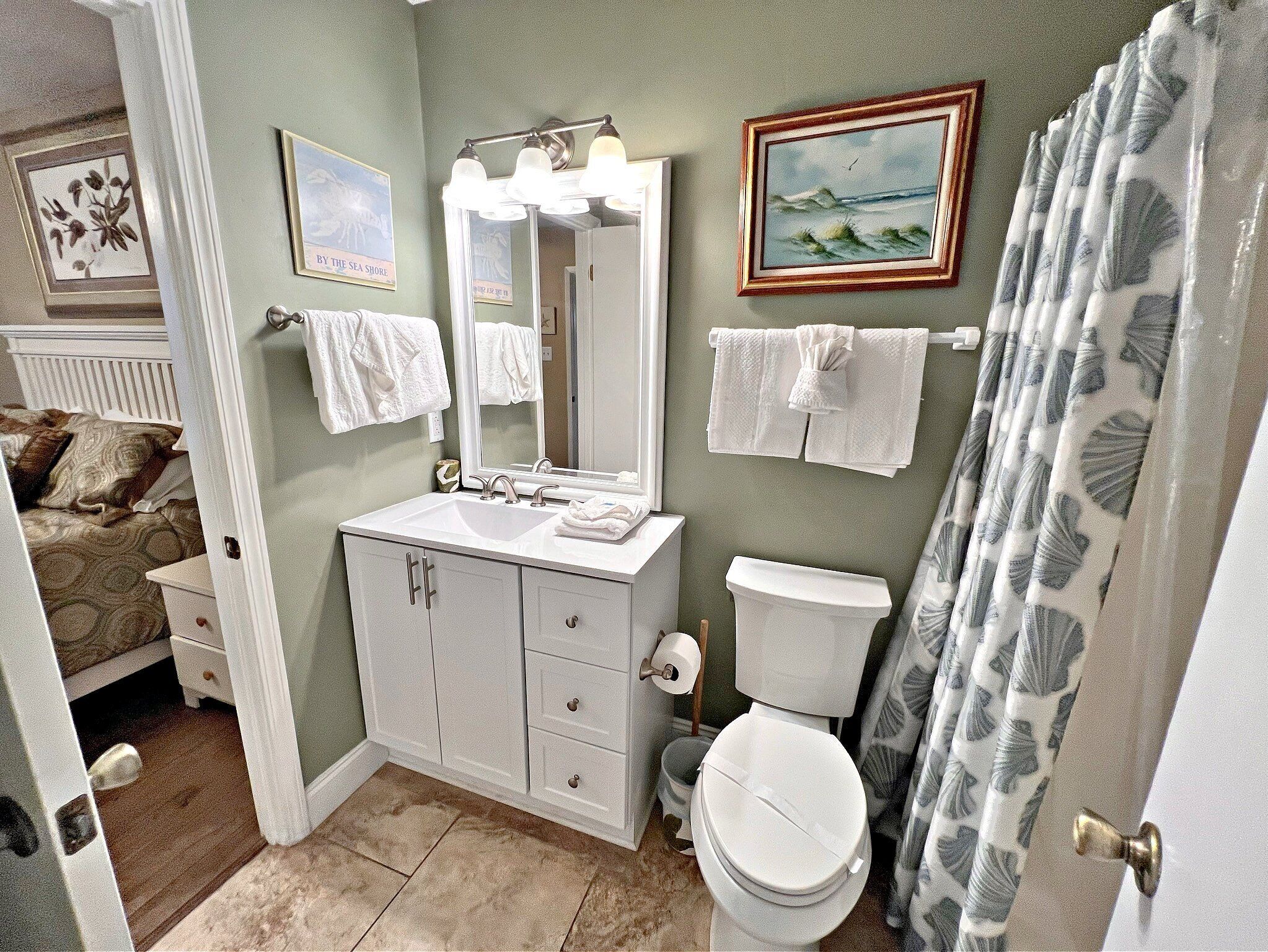 A bathroom with a sink, mirror, toilet, and shower curtain.