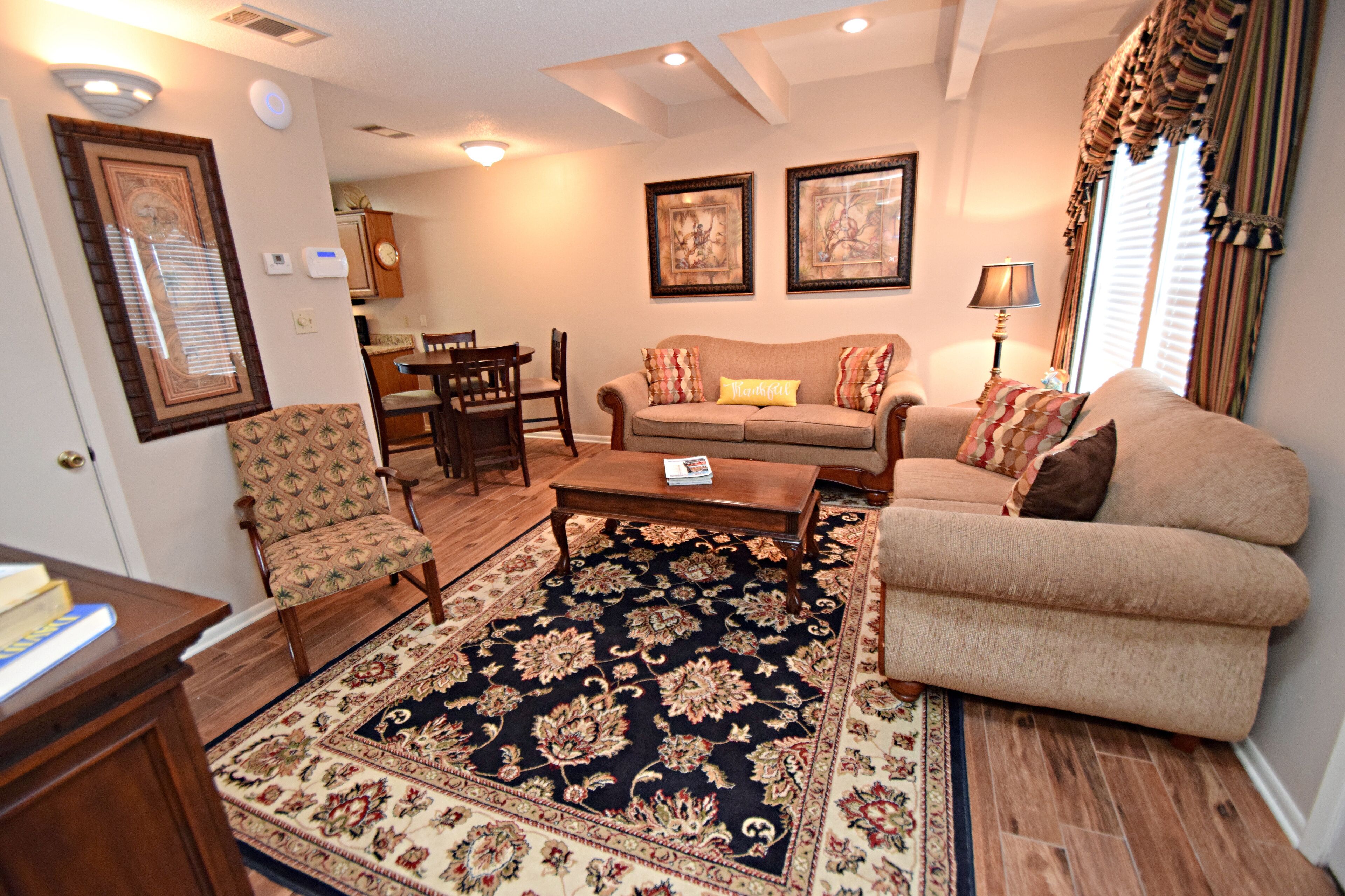 A living room with a sofa, armchairs, a coffee table, and a rug.