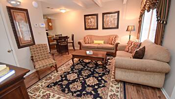 A living room with a sofa, armchairs, a coffee table, and a rug.