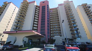 A multi-story residential building with balconies, a central entrance, and a parking area in front. - Phoenix II (Orange Beach)