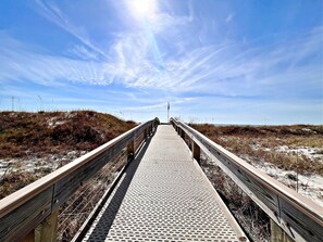 A wooden boardwalk leading to a beach with dunes and a clear sky. - Phoenix V (Orange Beach)