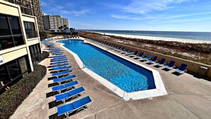 A swimming pool with lounge chairs, a beach view, and a hotel building. - Phoenix V (Orange Beach)
