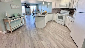 A kitchen with white cabinets, a granite countertop, and a built-in oven. - Regatta (Gulf Shores)
