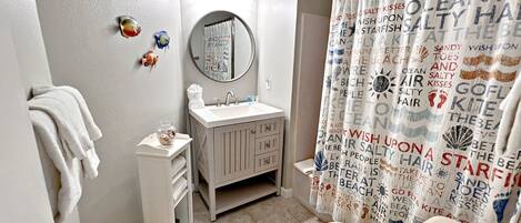 A bathroom with a toilet, sink, and shower curtain with text.