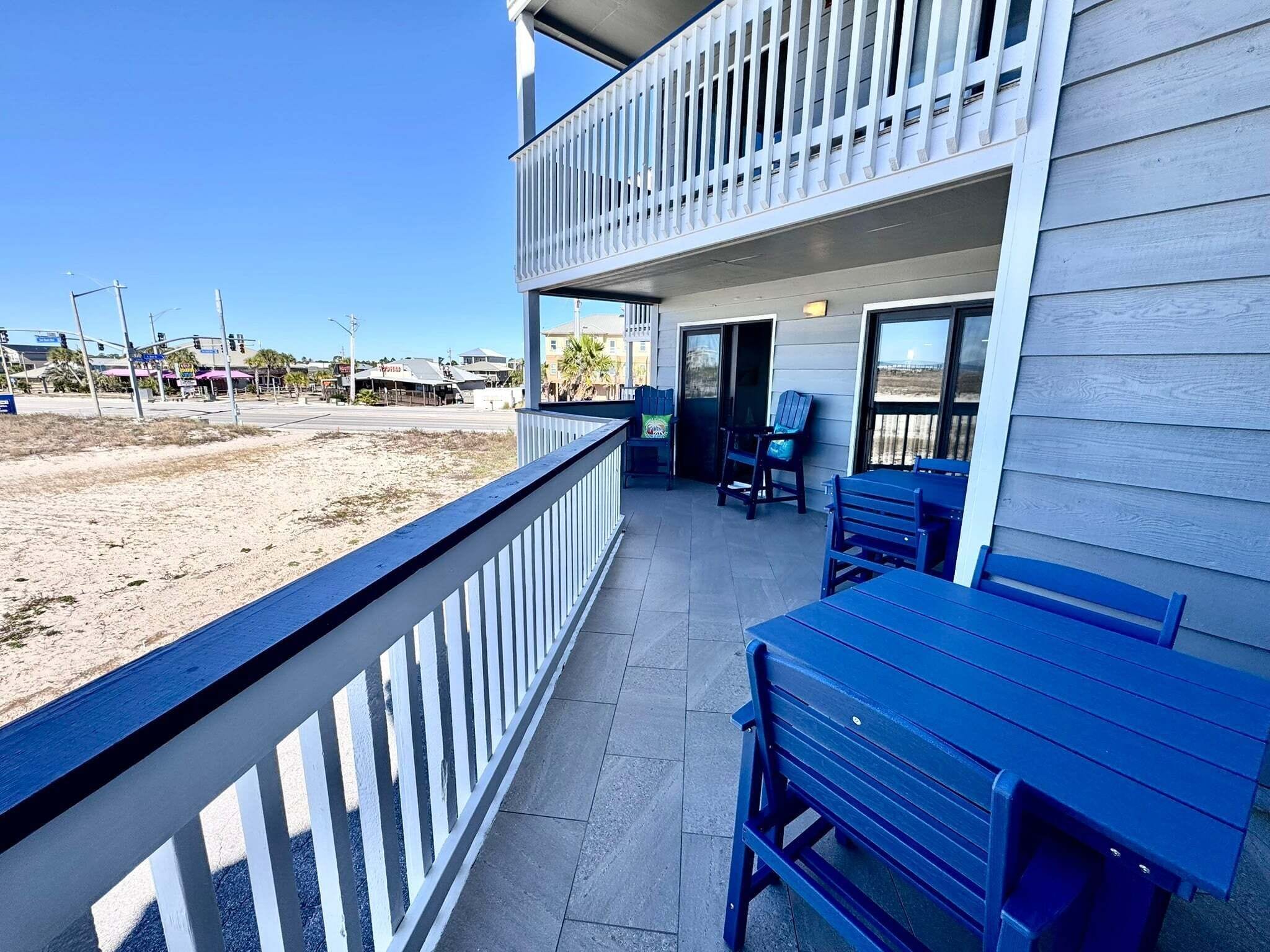 A two-story building with a balcony, outdoor seating, and a view of the beach.