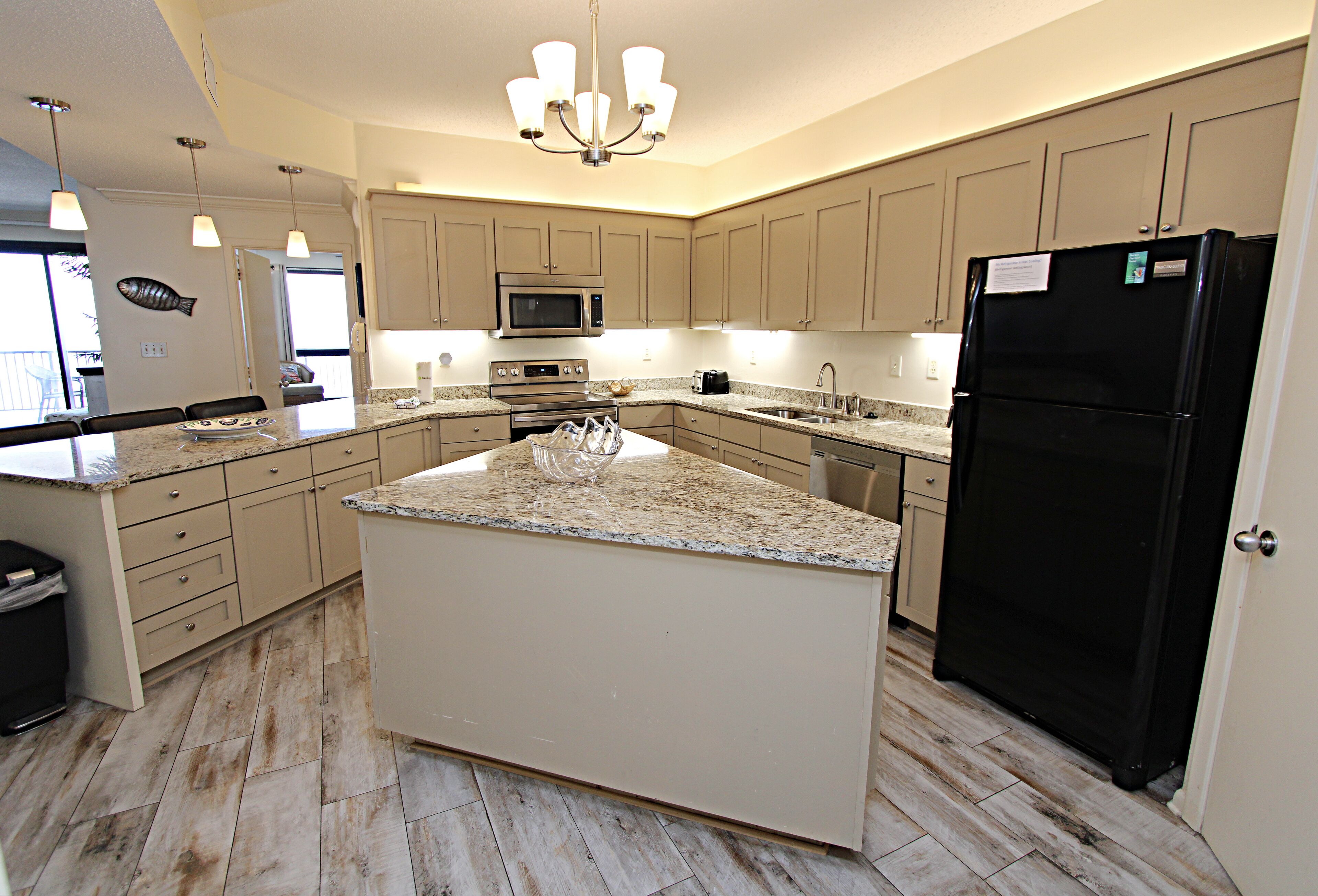 A spacious kitchen with a large island, stainless steel appliances, and light wood cabinetry.