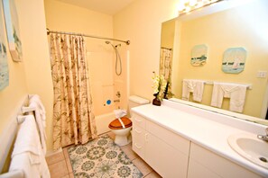 A bathroom with a shower, toilet, sink, and a mirror reflecting towels. - Romar Lakes (Orange Beach)