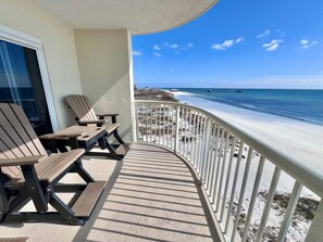 A balcony with a view of the beach, a table, and two chairs. - Royal Palms (Gulf Shores)
