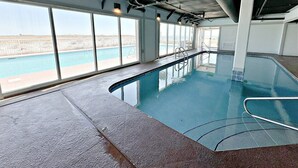 Une piscine intérieure dotée de grandes baies vitrées donnant sur l’extérieur.