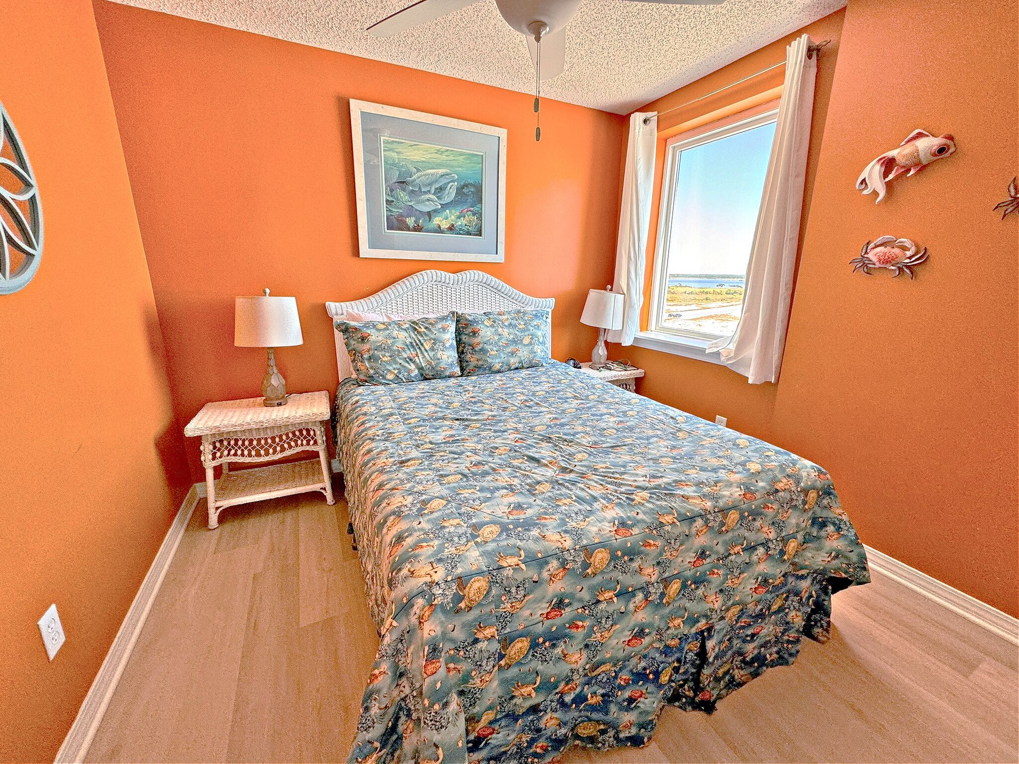 A bedroom with a bed, a nightstand, a lamp, a framed picture, and a window with a view.