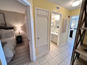 A hotel room with a bed, bedside table, lamp, and a bathroom visible through an open door. - Seacrest (Gulf Shores)