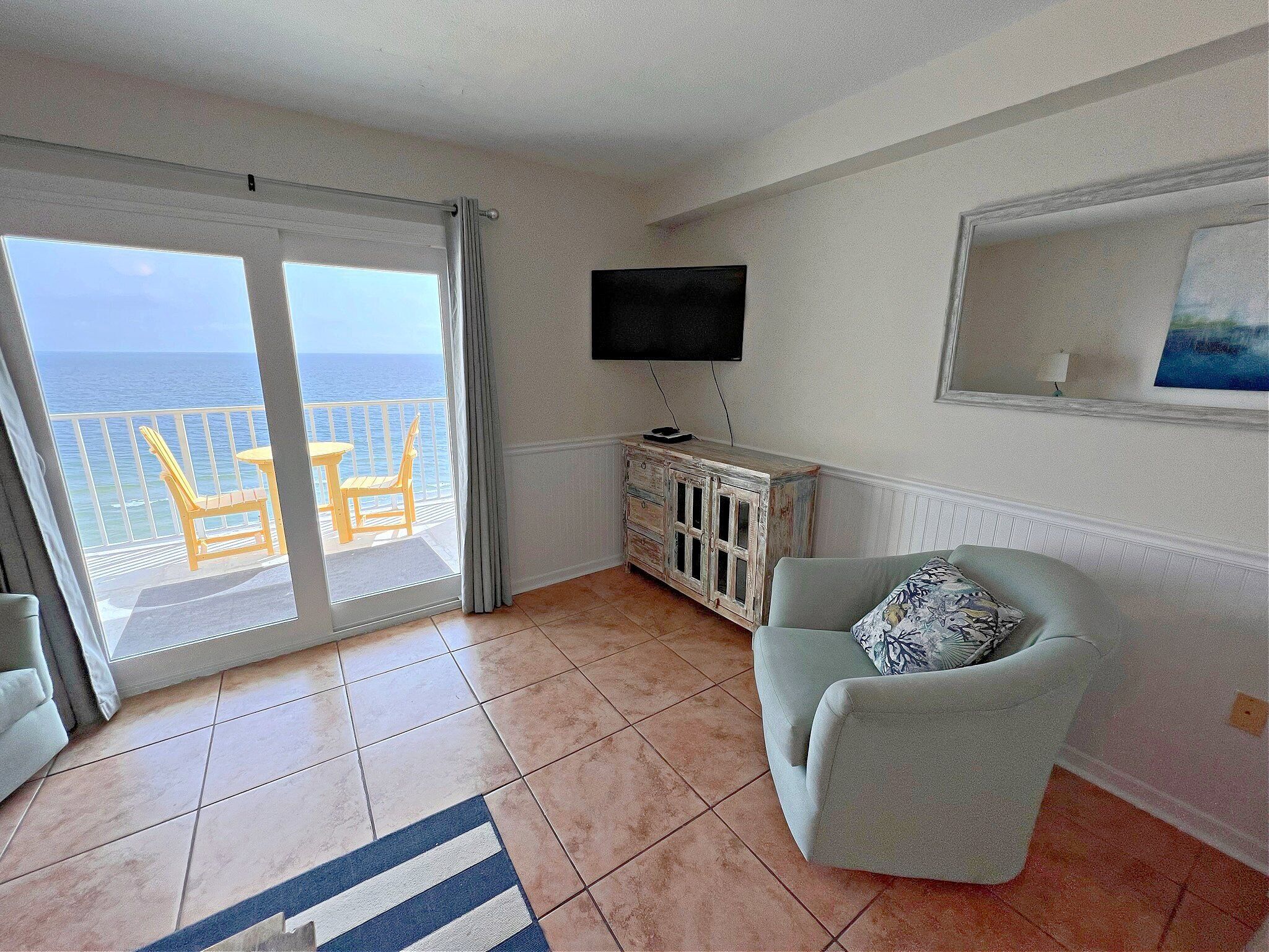 A living room with a balcony, a television, and a painting on the wall.