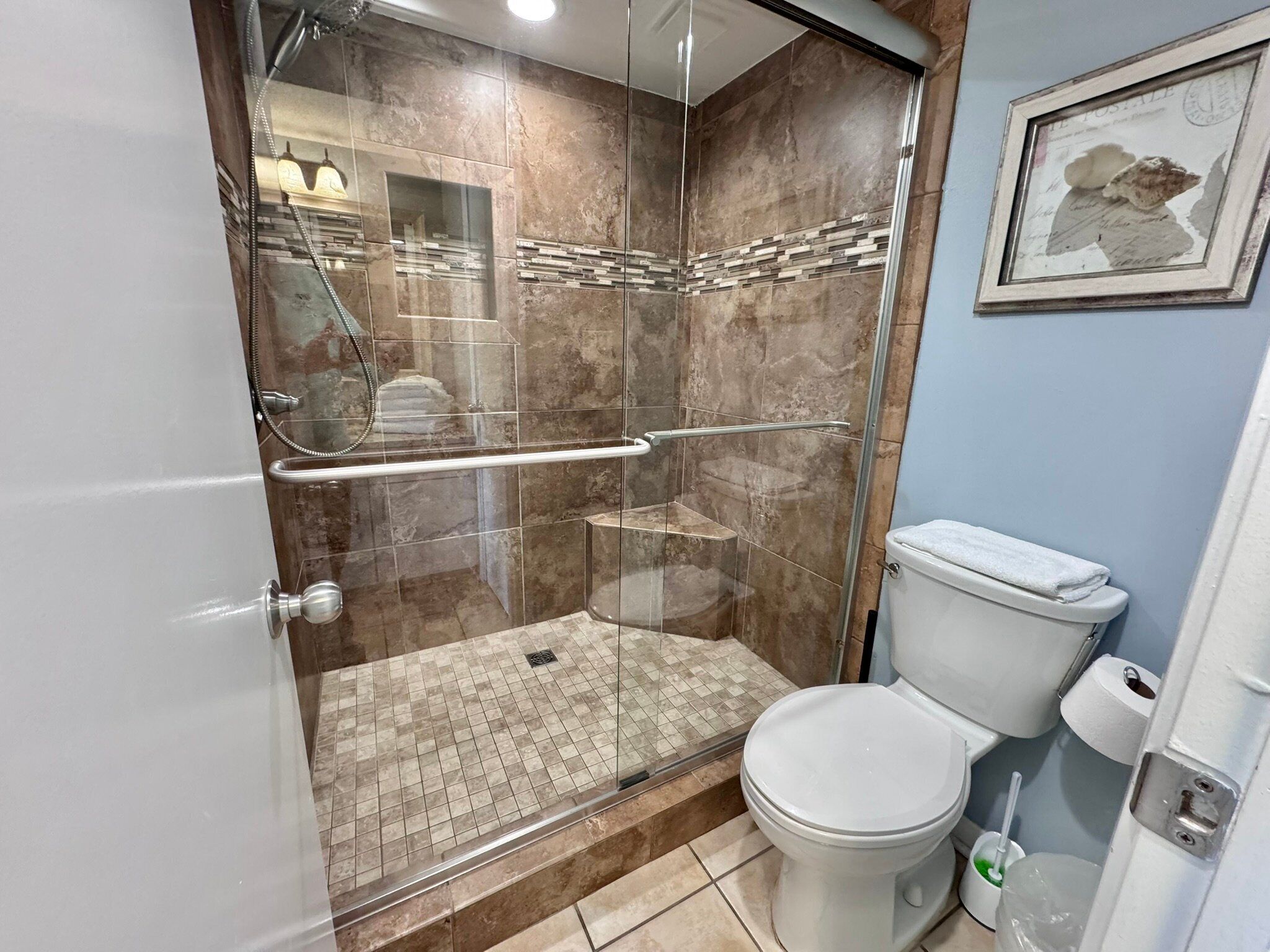 A modern bathroom with a glass-enclosed shower, a toilet, and a sink.