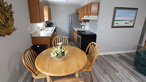 Una cocina compacta con armarios de madera, un refrigerador y una mesa de comedor con sillas.