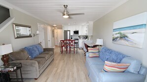 A spacious living room with a light blue sofa, a brown sofa, and a dining area with a red table and chairs. - Southwinds (Gulf Shores)