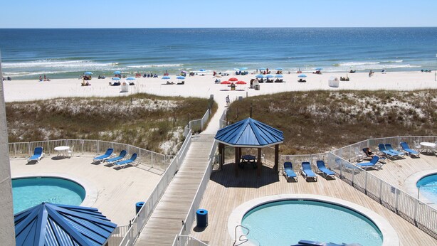 A beach resort with a pool area, lounge chairs, and a gazebo. - Sugar Beach (Orange Beach)